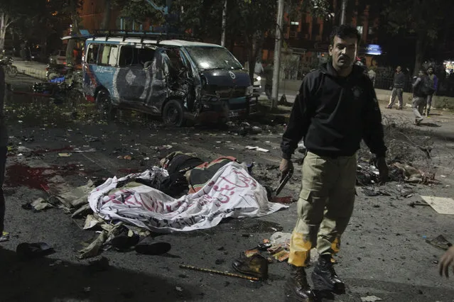 A police commando stands alert at the site of a deadly bombing, in Lahore, Pakistan, Monday, February 13, 2017. Pakistani police say a large bomb has struck a protest rally in the eastern city of Lahore, killing many people and wounding others. A local police official said the blast occurred when a man on a motorcycle rammed into the crowd of hundreds of pharmacists, who were protesting new amendments to a law governing drug sales. (Photo by K.M. Chaudhry/AP Photo)