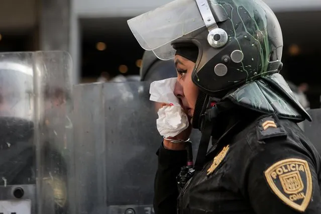 A policewoman uses a tissue during a protest to mark the International Day for the Elimination of Violence Against Women, in Mexico City, Mexico on November 25, 2021. (Photo by Raquel Cunha/Reuters)