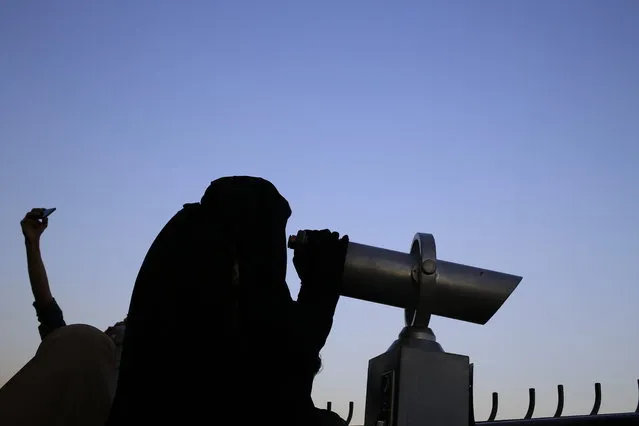 This Tuesday, May 5, 2015 photo shows an Egyptian woman looking through a telescope on the observation deck of the Cairo Tower in the Zamalek district in Cairo, Egypt. For most, the niqab is a choice. They do so out of their own interpretation of the Quran and the hadith, a collection of traditions and anecdotes about the Prophet Muhammad, believing that a woman's body should be covered out of modesty. (Photo by Hassan Ammar/AP Photo)