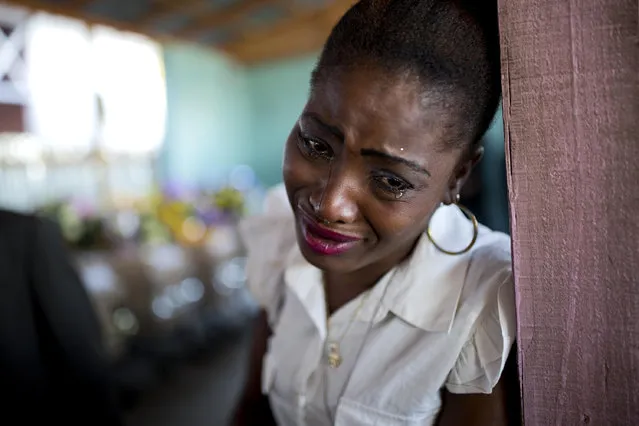 A woman cries near the coffin containing the body of a relative who died at the country's largest prison in Port-au-Prince, Haiti. Tuesday February 21, 2017. Relatives wailed in grief or stared stoically as flowers were placed on 20 caskets at a mass funeral for the latest group of inmates who died miserably in Haiti's largest prison, most without ever having been convicted of any crime. (Photo by Dieu Nalio Chery/AP Photo)