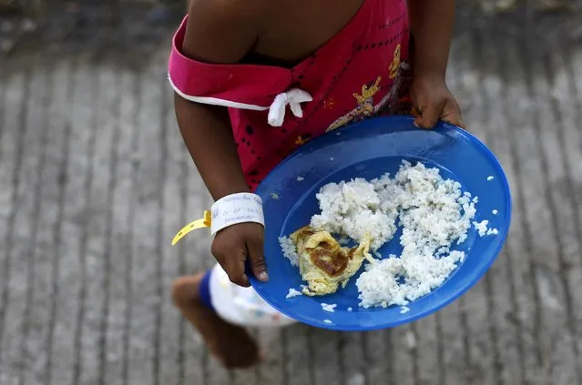 A Rohingya migrant child, who recently arrived in Indonesia by boat, holds her plate of breakfast at a shelter in Kuala Langsa, in Indonesia's Aceh Province, May 19, 2015. (Photo by Reuters/Beawiharta)