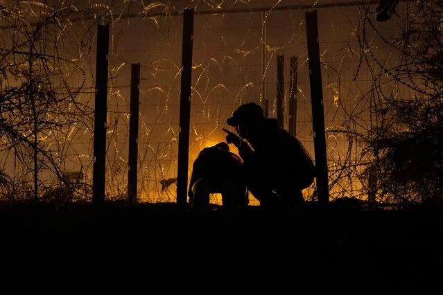 Men watch for U.S. authorities while shearing an opening through a razor wire-laden fence for a group of migrants from South and Central America to enter into the United States from along the bank of the Rio Grande River, in El Paso, Texas, U.S., April 2, 2024. (Photo by Cheney Orr/Reuters)