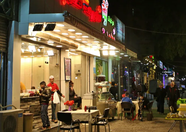 In this February 14, 2019 photo, shops and restaurants are open late at night in Baghdad, Iraq. For the first time in years, Iraq is not at war. (Photo by Khalid Mohammed/AP Photo)