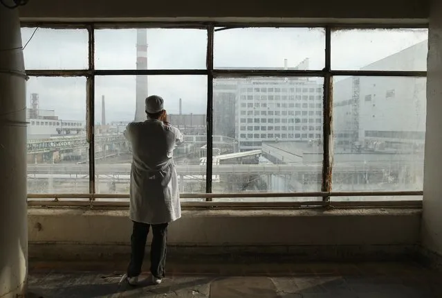 A visitor touring the former Chernobyl nuclear power plant takes a photo through a window looking towards facilities that house reactors one and two, September 29, 2015, near Chernobyl, Ukraine. Today, tour operators bring tourists in small groups to explore certain portions of the exclusion zone. (Photo by Sean Gallup/Getty Images)