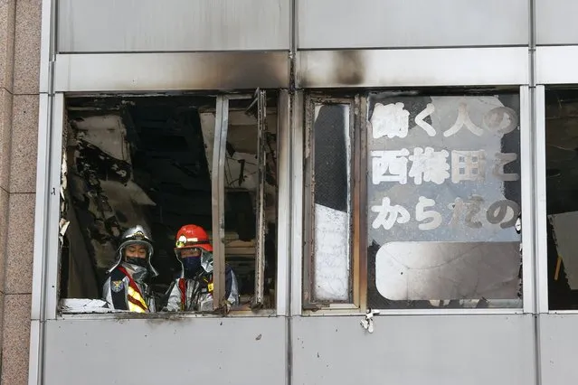 Firefighters stand on a floor at a building where a fire broke out in Osaka, western Japan Friday, December 17, 2021. Japan's NHK says a fire broke out in the building and dozens of people were feared dead. (Photo by Kyodo News via AP Photo)