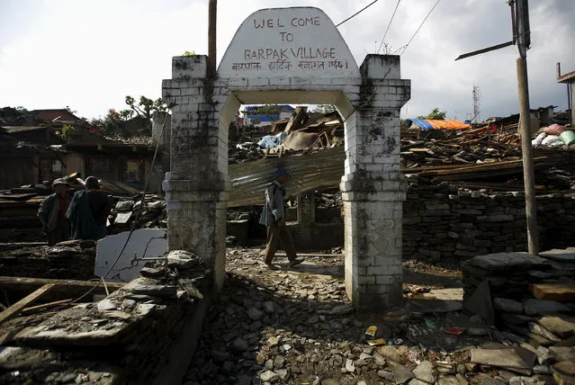 An earthquake victim, carrying a tin roof to rebuild a house, walks along the entrance gate of Barpak village in Gorkha district, Nepal, May 21, 2015. McGoldrick said the slow response was partly due to donor fatigue where governments were being torn between competing humanitarian crises across the world such as the civil conflict in Syria or in Yemen. (Photo by Navesh Chitrakar/Reuters)