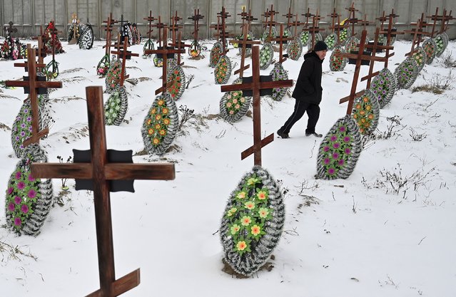 An elderly man walks among the graves of unidentified people, killed during Russian occupation, who were reburied from a mass grave in the small Ukrainian town of Bucha, near Kyiv, on January 12, 2023. (Photo by Sergei Supinsky/AFP Photo)