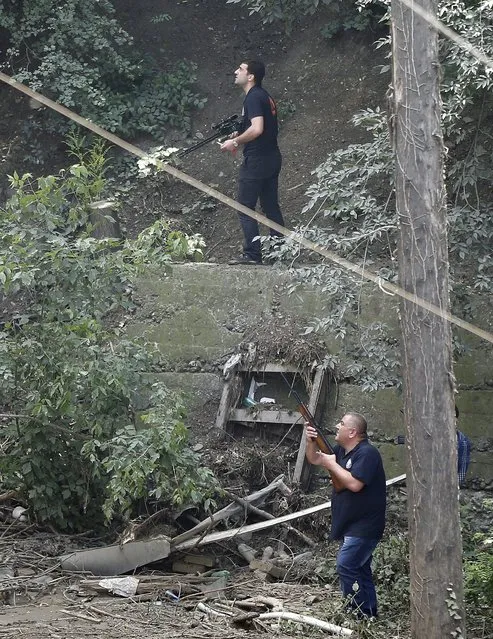 Armed municipality workers search for a white tiger that escaped when floods destroyed its enclosure, in Tbilisi, Georgia, June 17, 2015. Tigers, lions, bears and wolves were among more than 30 animals that escaped from a Georgian zoo and onto the streets of the capital Tbilisi on Sunday during floods that killed at least 12 people. REUTERS/David Mdzinarishvili