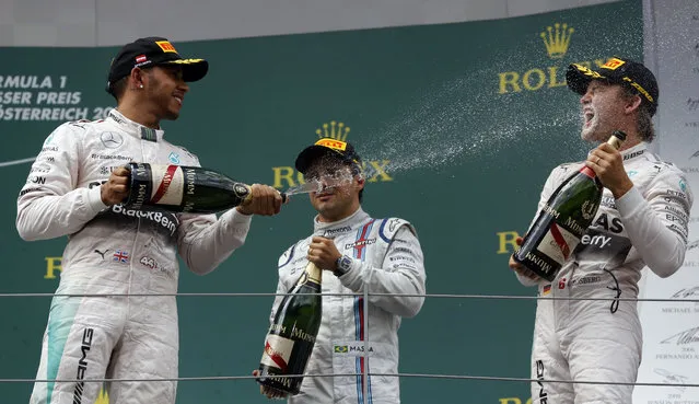 Second placed Mercedes driver Lewis Hamilton of Britain, left sprays champagne on the winner Mercedes driver Nico Rosberg of Germany, as third placed Williams driver Felipe Massa of Brazil, center, looks on, following the Formula One Grand Prix race, at the Red Bull Ring in Spielberg, southern Austria, Sunday, June 21, 2015. (AP Photo/Darko Bandic)
