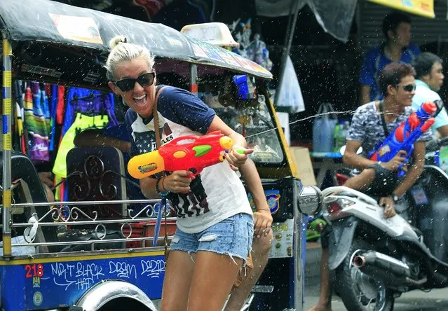 A tourists holds a water gun as she joins the upcoming annual Songkran Festival celebration, the Thai traditional New Year, also known as the water festival at Khao San road in Bangkok, Thailand, 12 April 2014. The three-day Songkran Festival runs from 13 to 15 April and is celebrated with splashing water and putting powder on each others faces as a symbolic sign of cleansing and washing away the sins from the old year. (Photo by Narong Sangnak/EPA)