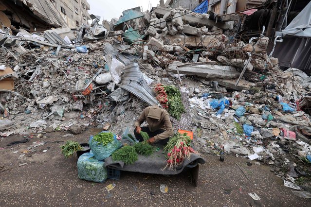 A young Palestinian man sells fresh vegetables in front of a building destroyed in Israeli strikes, ahead of Eid al-Fitr celebrations which conclude the Muslim holy fasting month of Ramadan, in Rafah in the southern Gaza Strip on April 5, 2024 amid the ongoing conflict between Israel and the militant group Hamas. (Photo by Mohammed Abed/AFP Photo)