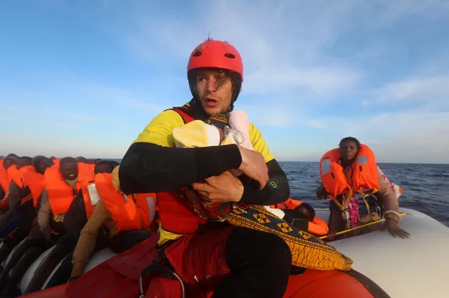 Spanish rescuer Daniel Calvelo, 26, carries a four-day-old baby girl into a RHIB, during a search and rescue operation by Spanish NGO Proactiva Open Arms, in central Mediterranean Sea, some 22 nautical miles north of the Libyan town of Sabratha, April 1, 2017. (Photo by Yannis Behrakis/Reuters)