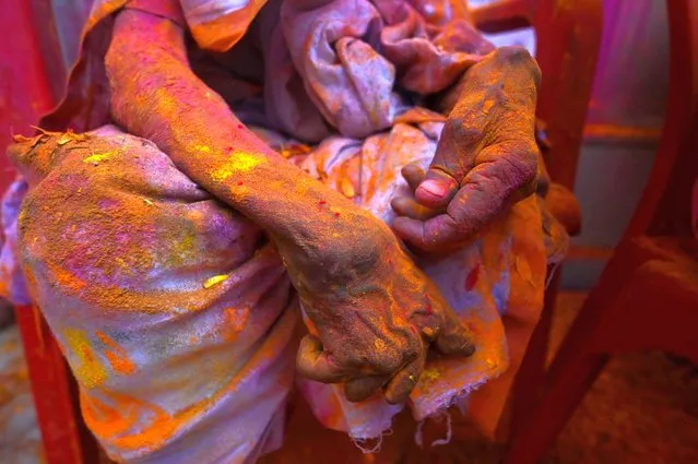A widow smeared with Gulal (colour powder) sits at a temple as she participates in Holi celebrations, the Hindu spring festival of colours,  in Vrindavan on March 15, 2022. (Photo by Money Sharma/AFP Photo)