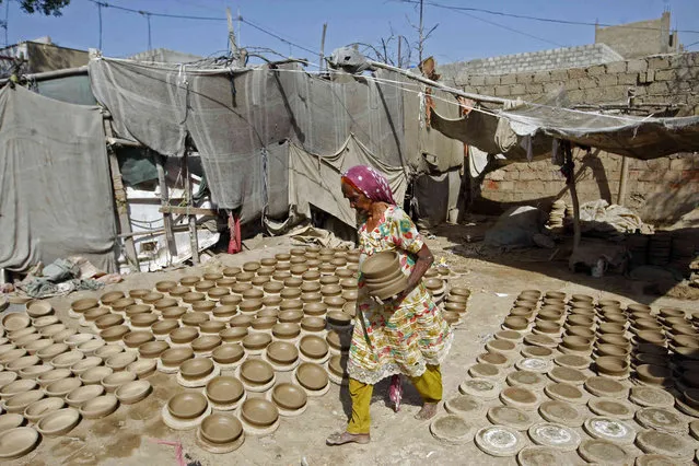 Katija Bibi, 90, carries pots at a pottery workshop on the outskirts of Karachi, Pakistan, Monday, March 7, 2022. (Photo by Fareed Khan/AP Photo)