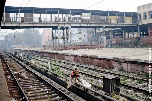 A girl collects cardboard, to be sold, from the tracks at the  Nizamuddin Railway Station in New Delhi, India
