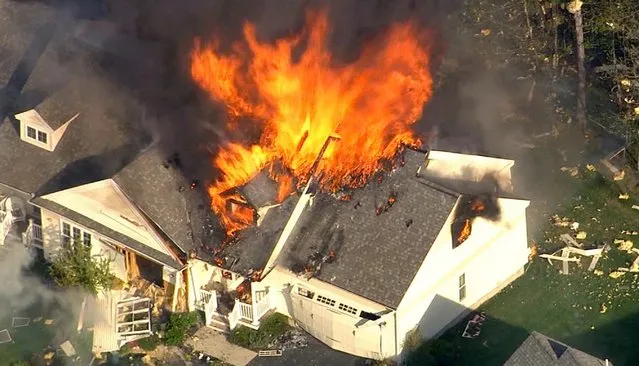 In this frame grab from television helicopter video, a home bursts into flames in Brentwood, N.H., Monday May 12, 2014. Shots were fired just before the fire, which involved a police officer, according to the New Hampshire State Police. (Photo by AP Photo/WHDH-TV 7)