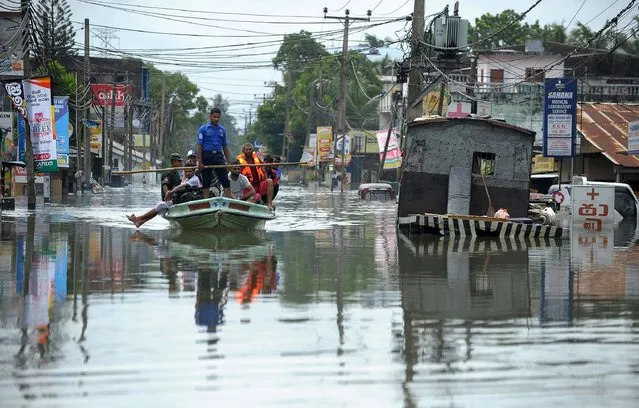 Sri Lankan navy and army personnel evacuate residents following flooding in the Kolonnawa suburb of Colombo on May 20, 2016. Desperate Sri Lankans clambered onto rubber dinghies and makeshift rafts May 20 to flee their homes in the flooded capital Colombo as fresh downpours elsewhere stalled rescue efforts at disaster zones. The heaviest rains in a quarter of a century have pounded the island since last weekend, sparking huge landslides that have buried victims in up to 50 feet (15 metres) of mud. (Photo by Ishara S.Kodikara/AFP Photo)