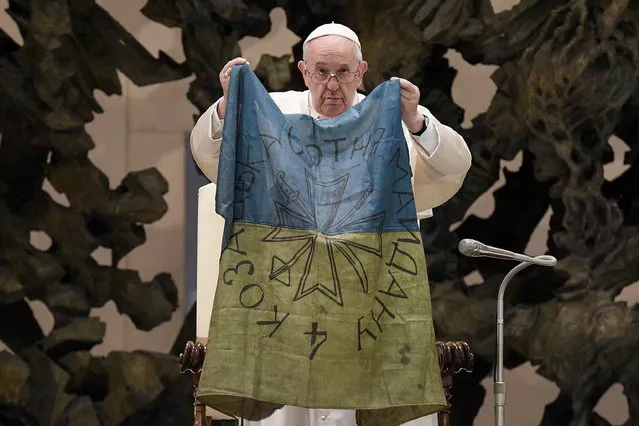 A handout picture provided by the Vatican Media shows Pope Francis holding a flag of Ukraine that was sent to him from the Ukrainian town of Bucha during the weekly general audience in the Paul VI Audience Hall, in Vatican City, 06 April 2022. The pontiff lamented the “massacre of Bucha”, in the Kyiv suburb where dozens of bodies in civilian clothing have been found, and renewed his calls for an end to the war in Ukraine. (Photo by Vatican Media Handout/EPA/EFE)