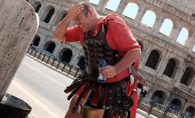 A street artist dressed as ancient Roman gets some refreshment from a fountain in front of the Coliseum in Rome on July 17, 2015. The next few days will see a record heat in many Italian cities with temperatures above 40 degrees and humidity. (Photo by Alberto Pizzoli/AFP Photo)