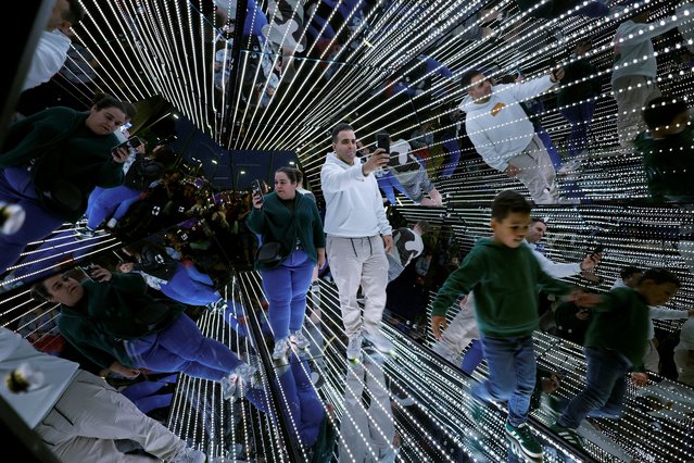 People walk through Passengers, by Tetro+A & Yam, during The White Night (in Basque, Gau Zuria) commemorating the founding of the Villa of Bilbao with light shows, music, art and literature at venues throughout the city, in Bilbao, Spain, on June 15, 2024. (Photo by Vincent West/Reuters)