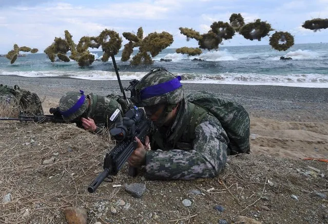 South Korean Marines take position on a beach as amphibious assault vehicles fire smoke shells during a joint landing operation by US and South Korean Marines in the southeastern port of Pohang on April 2, 2017. The drill is part of the annual joint exercise Foal Eagle to enhance the combat readiness of the US and South Korea supporting forces in defense of the Korean Peninsula. (Photo by Jung Yeon-Je/AFP Photo)