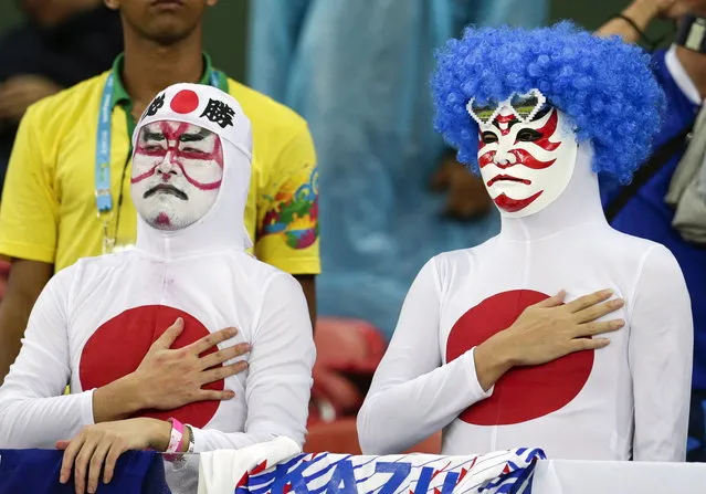 Japanese fans listen to their nation's national anthem before the group C World Cup soccer match between Ivory Coast and Japan at the Arena Pernambuco in Recife, Brazil, Saturday, June 14, 2014. (Photo by Petr David Josek/AP Photo)