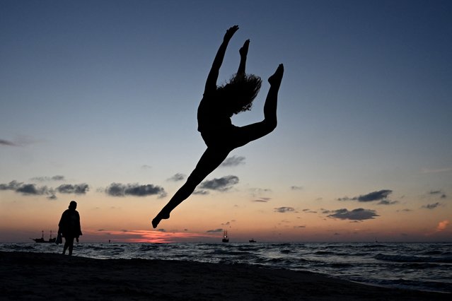 A member of the Grupa Magnifica acrobatics club poses for a photo on the Baltic Sea beach during sunset in the town of Leba, Pomeranian region, on August 6, 2024. (Photo by Sergei Gapon/AFP Photo)