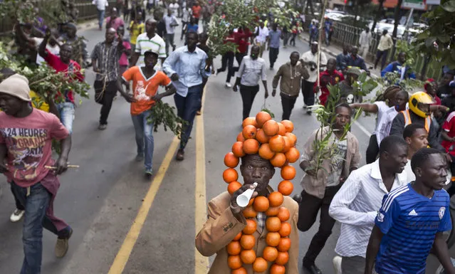 Opposition demonstrators calling for the disbandment of the electoral commission over allegations of bias and corruption, one wearing a headdress of plastic oranges, the party color, protest in downtown Nairobi, Kenya Monday, June 6, 2016. (Photo by Ben Curtis/AP Photo)