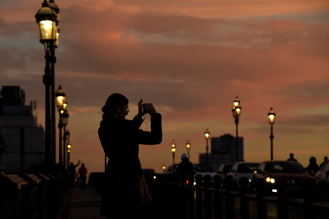 A woman takes a picture of the setting sun in the Chelsea area of London, Britain December 11, 2016. (Photo by Clodagh Kilcoyne/Reuters)