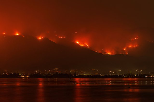 The Airport Fire burns along the hillside and is reflected in Lake Elsinore, California on September 10, 2024. (Photo by Mike Blake/Reuters)