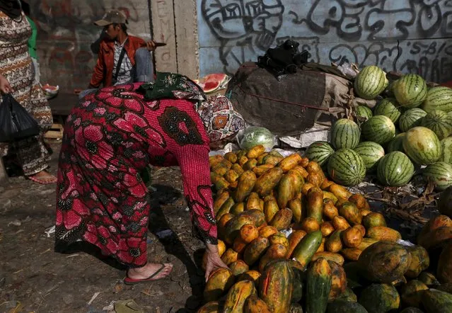 A woman holds a papaya to buy it at a vegetable market near Duri train station in Jakarta, Indonesia August 3, 2015. (Photo by Reuters/Beawiharta)