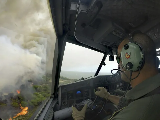 In this June 25, 2017 image made available by the Spanish Airforce on June 26, 2017, a Spanish firefighting plane flies over the fires in the Moguer area in southern Spain. A forest fire in southern Spain has forced the evacuation of 1,000 people and is threatening Donana National Park, one of Spain's most important nature reserves and a UNESCO World Heritage site since 1994, and famous for its biodiversity, authorities said Sunday. (Photo by Spanish Airforce via AP Photo)