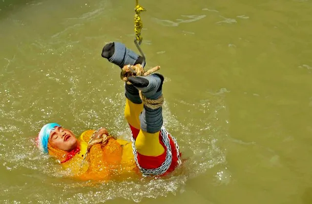 In this photo taken on June 16, 2019 Indian stuntman Chanchal Lahiri, known by his stage name “Jadugar Mandrake”, is lowered into the Ganges river, while tied up with steel chains and ropes, in Kolkata. An Indian magician who went missing after being lowered into a river tied up in chains and ropes in a Houdini-inspired stunt is feared drowned, police said June 17. (Photo by AFP Photo/Stringer)