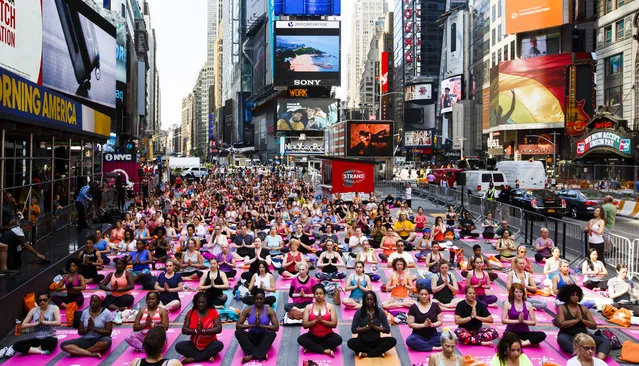 People participate in a group yoga class in Times Square as part of the 14th annual “Solstice in Times Square: Mind Over Madness Yoga” to mark the summer solstice in New York, New York, USA, 20 June 2016. (Photo by Justin Lane/EPA)