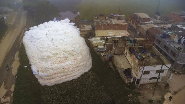 Aerial view shows pungent foam which formed in a polluted river and invaded the Los Puentes neighbourhood, in Mosquera, west of Bogota, on April 26, 2022. (Photo by Juan Barreto/AFP Photo)