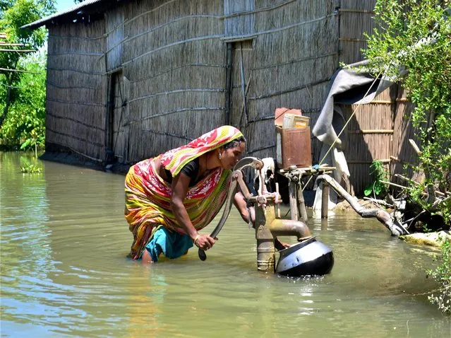 A woman collects drinking water from a hand-pump in the flood affected area in Kamrup district of Assam on Friday, July 14, 2017. (Photo by Press Trust of India Photo)