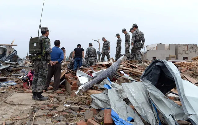 Chinese paramilitary policemen search for survivors on the rubble of a destroyed building in Funing county in Yancheng city in eastern China's Jiangsu Province Friday, June 24, 2016. One day after the storm, rescuers on Friday continued searching for survivors in this densely populated area of farms and factories on the outskirts of the major city of Yancheng in Jiangsu province. The twister was one of the most extreme weather events witnessed by China in recent years, leaving a swath of destruction with destroyed buildings, smashed trees and flipped vehicles on their roofs. (Photo by Chinatopix via AP Photo)