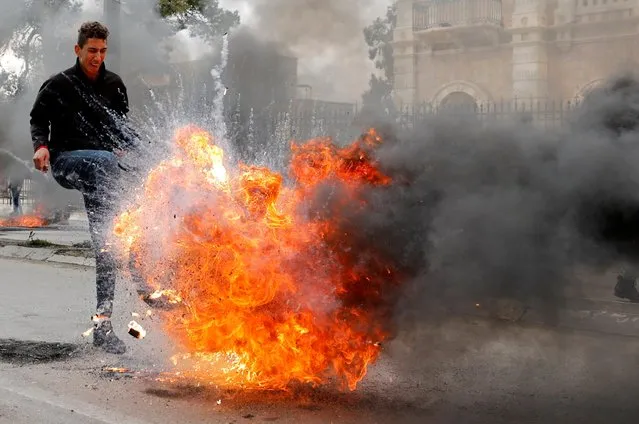 A Palestinian demonstrator kicks a burning tire during a protest against U.S. President Donald Trump's Middle East peace plan, in Bethlehem in the Israeli-occupied West Bank on January 29, 2020. (Photo by Mussa Qawasma/Reuters)