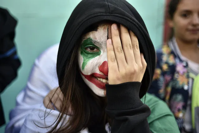 An Algerian demonstrator wearing face paint in the colours of the national flag takes part in an anti-government demonstration in the capital Algiers on November 1, 2019. Demonstrators converged on Algiers in their thousands for a massive anti-government rally called to coincide with official celebrations of the anniversary of the war that won Algeria's independence from France. (Photo by Ryad Kramdi/AFP Photo)