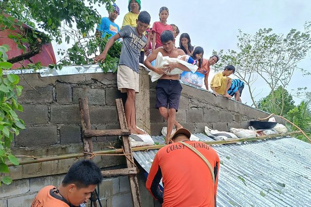 This handout photo taken and released on October 23, 2024 by the Philippine Coast Guard (PCG) shows residents affected by Tropical Storm Trami being evacuated from the roofs of their submerged houses, in Libon town, Albay province, South of Manila. - Philippine rescuers waded through chest-deep floodwaters October 23 to reach residents trapped by Tropical Storm Trami, which has forced thousands to evacuate as it barrels towards the country's east coast. (Photo by  Philippine Coast Guard (PCG)/Handout via AFP Photo)