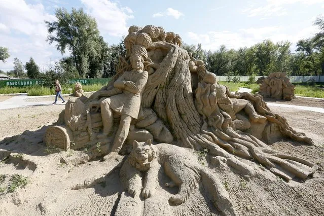 A visitor walks past the “Lukomorie” sand sculpture created by Russian artists Ruslan Knyazev, Yegor Tulyakov and Oleg Molchanov based on stories of Russian poet and writer Alexander Pushkin, at the “Favorite Book” thematic exhibition of sand sculptures in the Siberian city of Krasnoyarsk, Russia, August 16, 2015. The exhibition is created by professional artists from several Siberian cities and students of the Krasnoyarsk State Arts Institute, according to organizers. (Photo by Ilya Naymushin/Reuters)