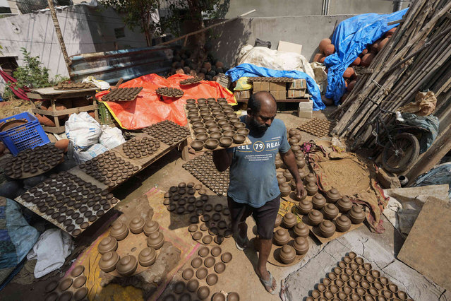 A potter carries earthen lamps to dry ahead of Diwali, the Hindu festival of lights, which will be celebrated across the country on 31 October, in Hyderabad, India, Friday, October 25, 2024. (Photo by Mahesh Kumar A./AP Photo)