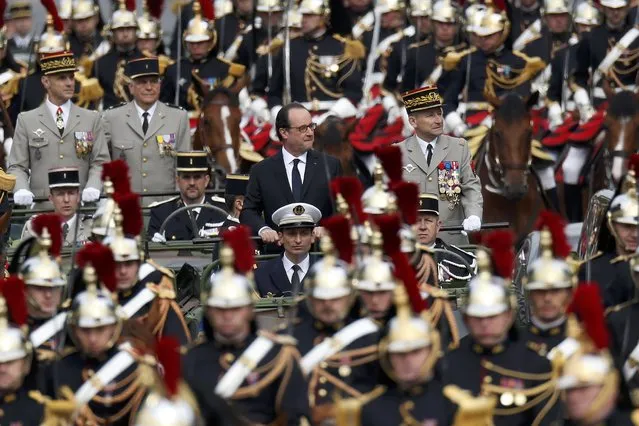 French President Francois Hollande (C) stands at attention in the command car as he reviews the troops while descending the Champs Elysees at the start of the traditional Bastille Day military parade in Paris, France, July 14, 2016. (Photo by Benoit Tessier/Reuters)