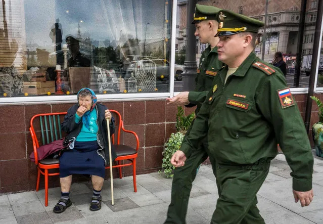 Two Russian military men pass by an elderly woman resting on a bench in Moscow on September 7, 2017. (Photo by Mladen Antonov/AFP Photo)