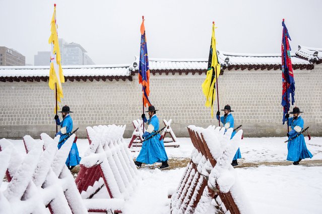 Palace guards walk away at the end of their shift at Gyeongbokgung Palace amid heavy snowfall in central Seoul on November 27, 2024. (Photo by Anthony Wallace/AFP Photo)