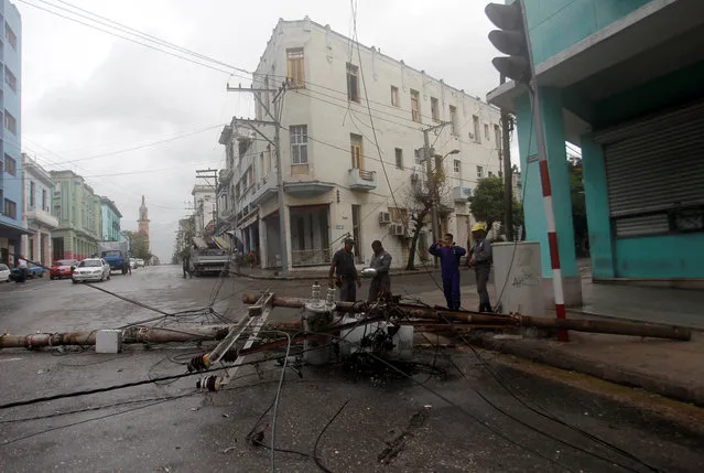 Workers stand near an electricity pole that was knocked down by heavy winds, ahead of the passing of Hurricane Irma, in Havana, Cuba September 9, 2017. (Photo by Reuters/Stringer)