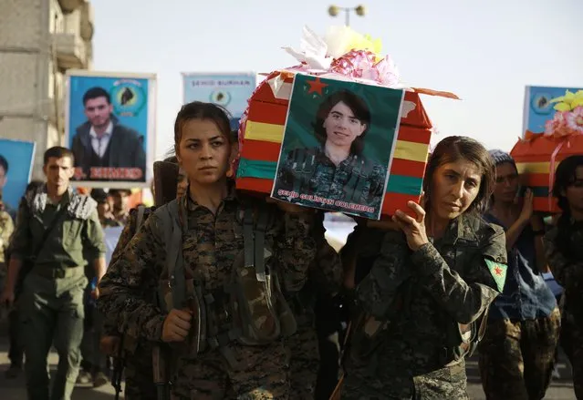 Syrian-Kurdish women carry the coffin of a female fighter in Syria's northeastern city of Qamishli on July 21, 2016 during the funeral of sixteen fighters killed battling the Islamic State (IS) group in Manbij. US-backed fighters gave the Islamic State group 48 hours to leave the battleground Syrian town of Manbij, after US-led air strikes nearby killed scores reported to be civilians. (Photo by Delil Souleiman/AFP Photo)