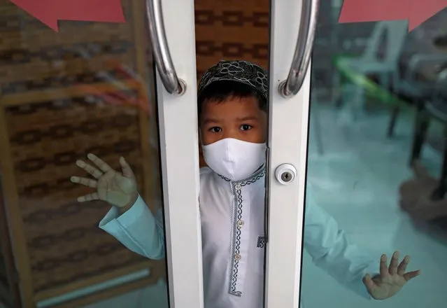 A Muslim boy wearing a protective face mask looks from his home near a closed mosque on the first day of the holy fasting month of Ramadan, amid the coronavirus disease (COVID-19) outbreak, in Bangkok, Thailand on April 24, 2020. (Photo by Soe Zeya Tun/Reuters)