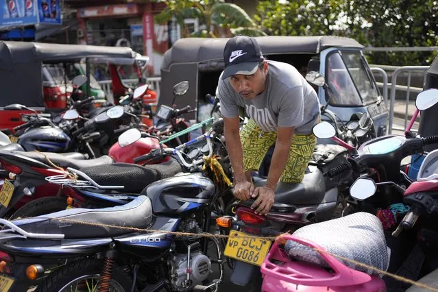 A man navigates his way through motorbikes parked for fuel at a fuel station in Colombo, Sri Lanka, Wednesday, July 27, 2022. Sri Lanka's economic crisis has left the nation's 22 million people struggling with shortages of essentials, including medicine, fuel and food. (Photo by Eranga Jayawardena/AP Photo)