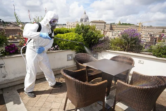 A worker disinfects the roof terrace of the Atlantic hotel, in Rome, Wednesday, April 29, 2020. After seven weeks in lockdown to contain one of the world’s worst outbreaks of COVID-19, Italians are regaining some freedoms, starting on May 4, public parks and gardens will re-open and people will be able to visit relatives who live in the same region. (Photo by Andrew Medichini/AP Photo)